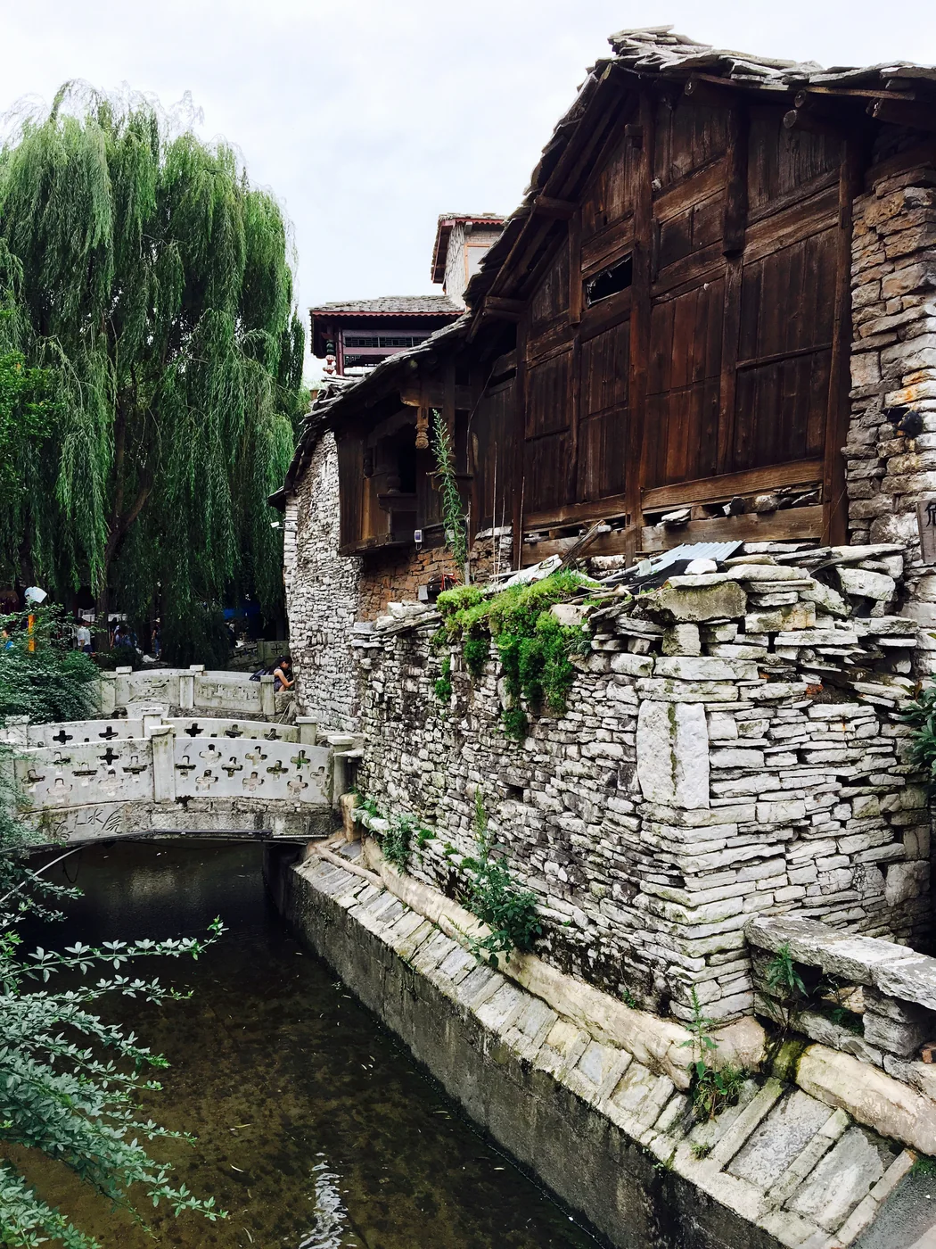 Stone and timber buildings beside a water channel at Tianlong Tunpu in 2017