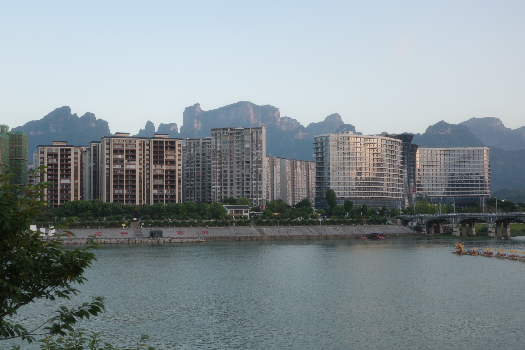 河畔的张家界市区楼房，背后为群山。