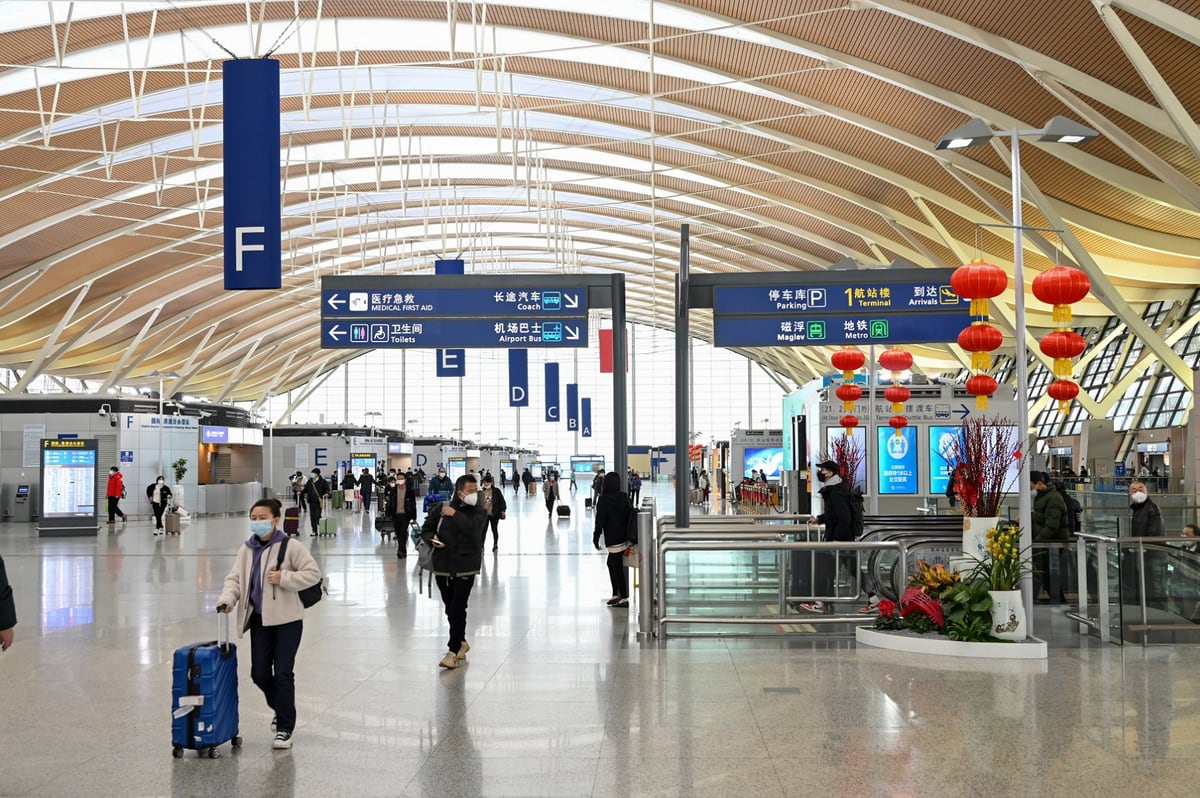 Airport terminal hall with signs for arrivals, metro, maglev and ground transport.