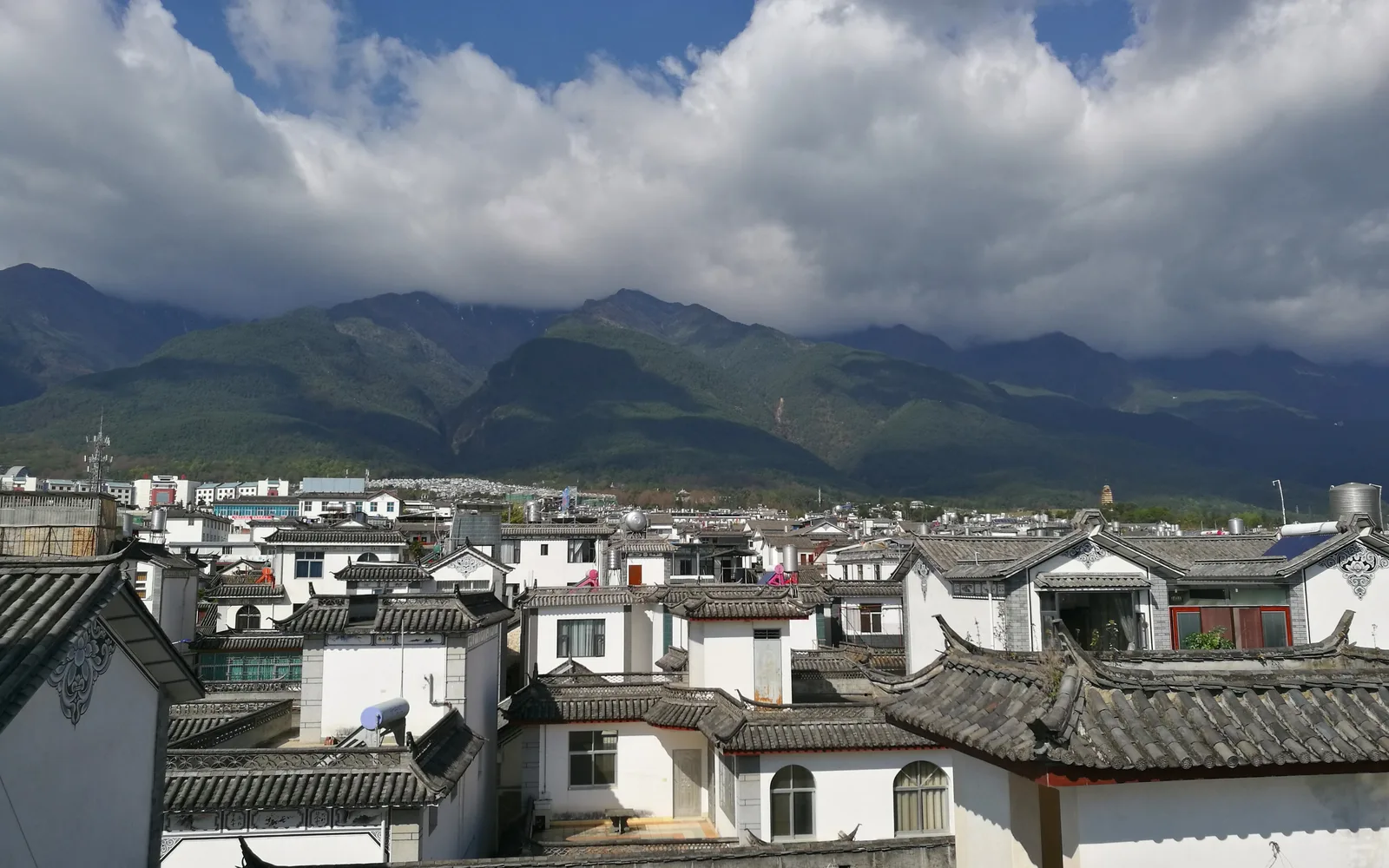 White-walled, grey-tiled Bai houses of Dali Old Town with the Cangshan mountains under cloud behind them