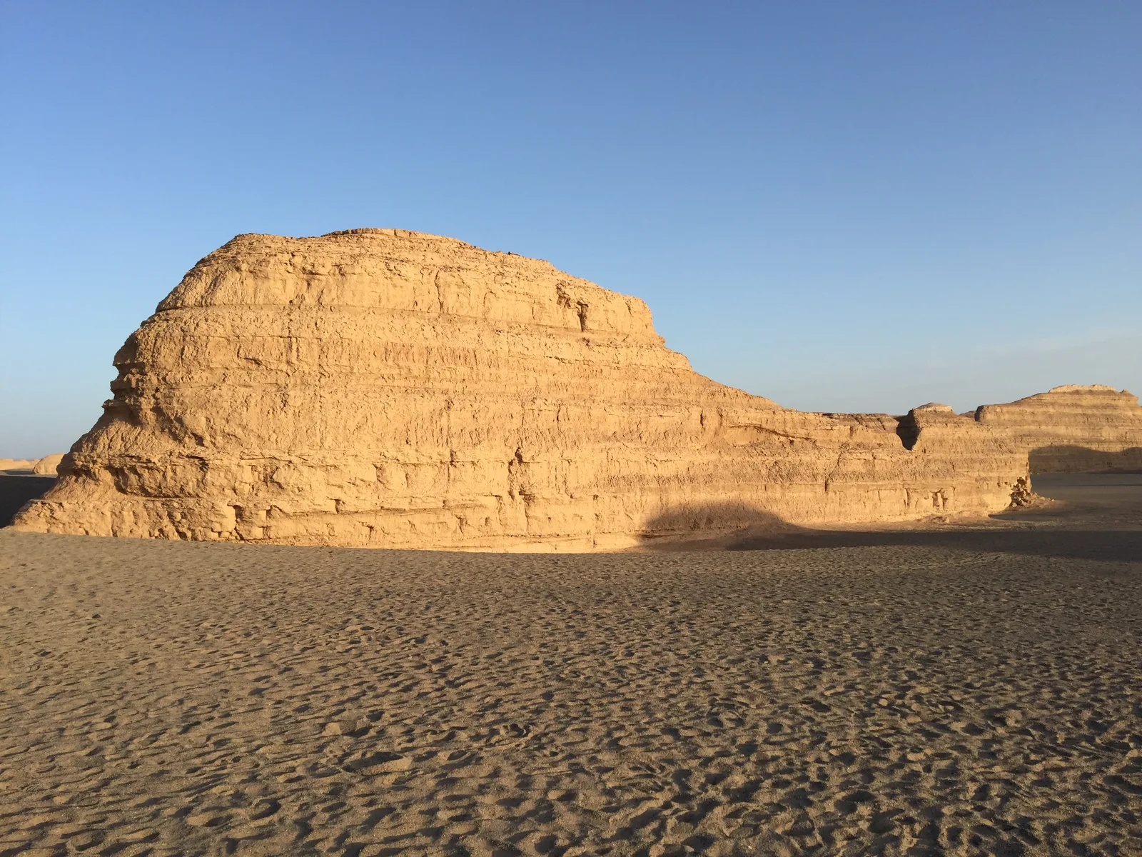 A long wind-carved yardang ridge lit by low sun in the Gobi near Dunhuang