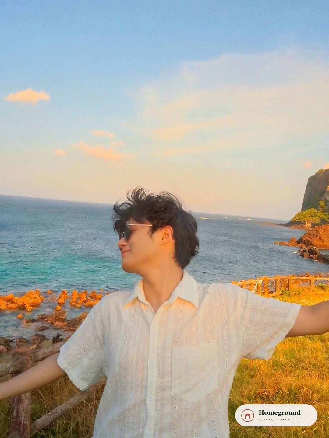 흰 셔츠를 입고 해 질 무렵 바닷가에 서 있는 Kevin.