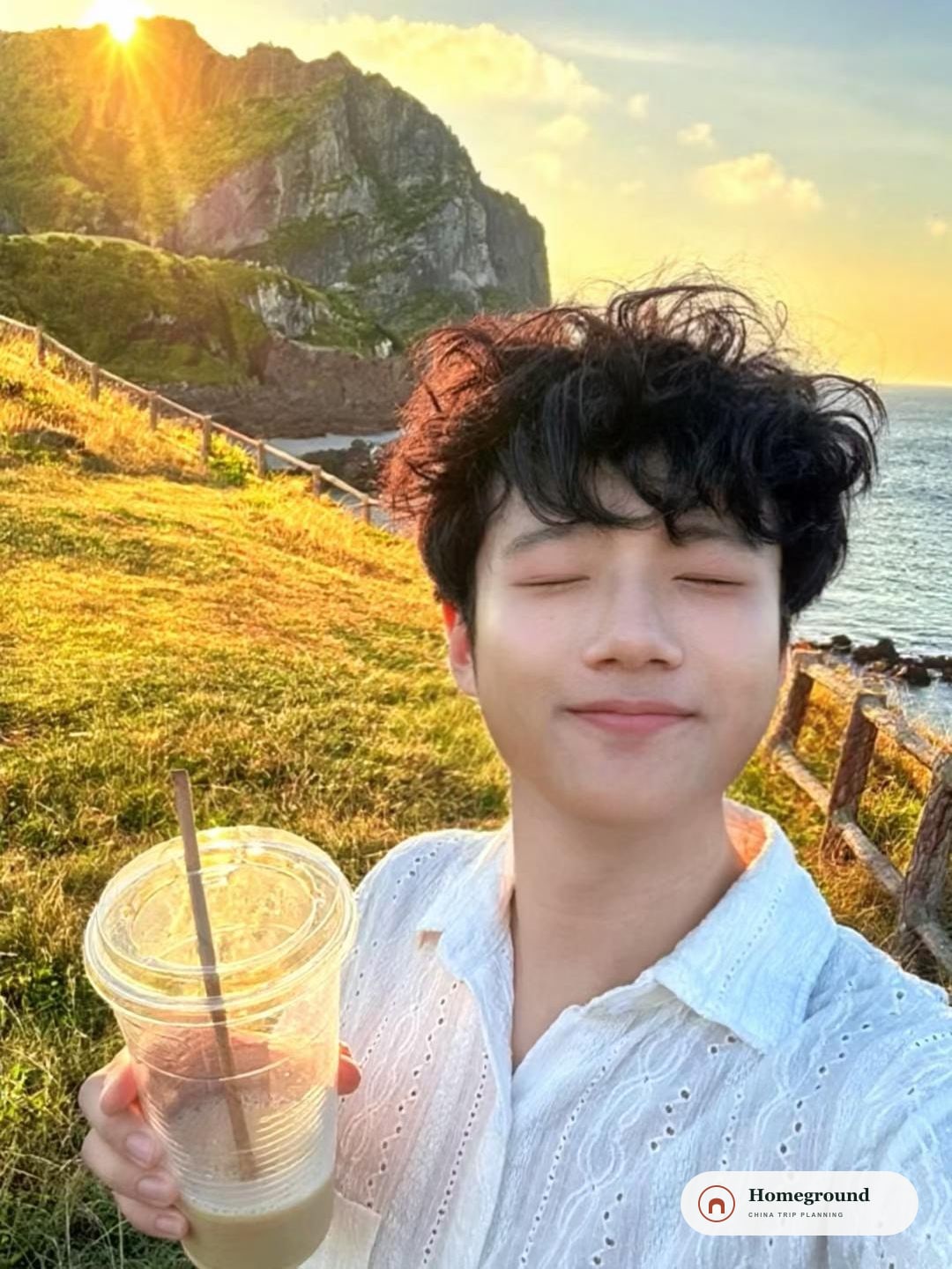 해 질 무렵 바닷가에서 음료를 들고 눈을 감은 채 웃는 Kevin.