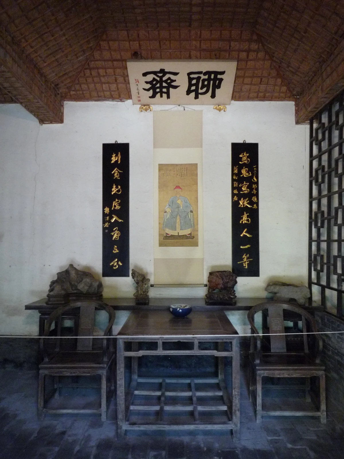 A room identified as Liaozhai in Pu Songling's former-residence compound, with a portrait display, furniture and viewing barrier.