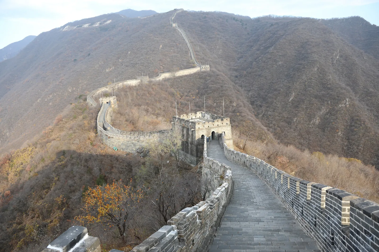 Tour de guet de la Grande Muraille de Mutianyu sur une crête boisée aux couleurs d’automne.