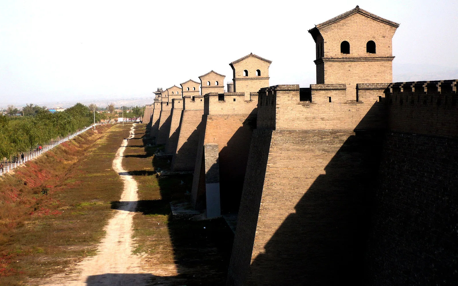 Pingyao’s brick city wall and a line of watchtowers running into the distance in low autumn light