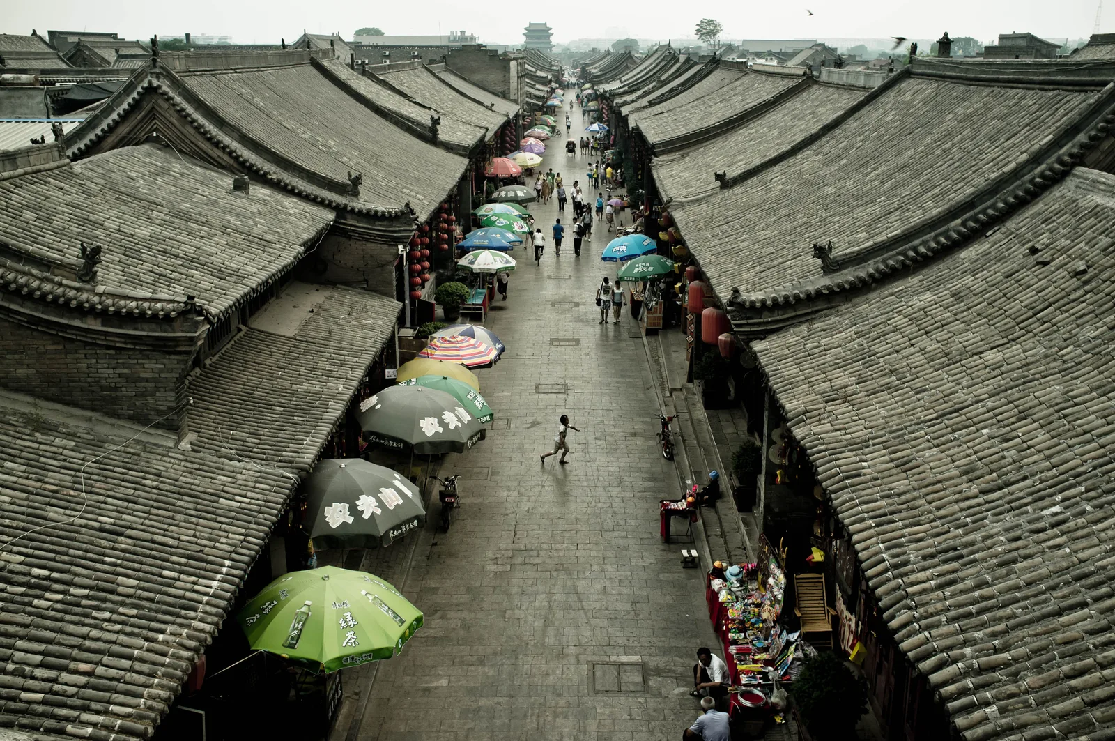 South Street in Pingyao seen from the Market Tower, with grey-tiled roofs on both sides and market umbrellas along the street