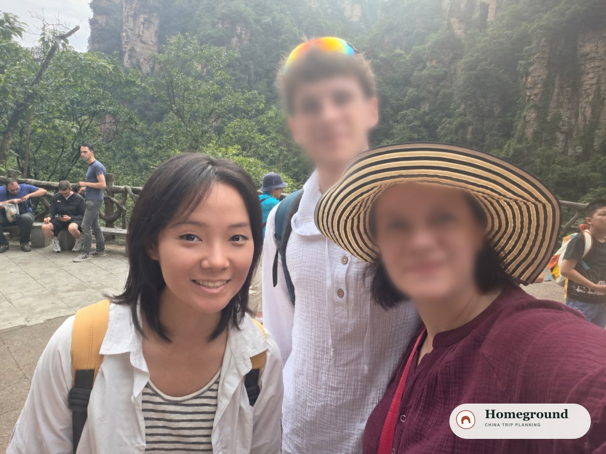 Tantan with guests against the forested mountain landscape of Zhangjiajie; guest faces are blurred for privacy.