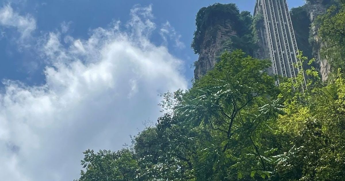The Bailong Elevator rising against a sandstone cliff under a blue sky in Zhangjiajie.