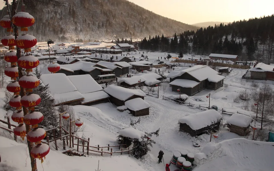 Snow-covered wooden houses and red lanterns in China Snow Town