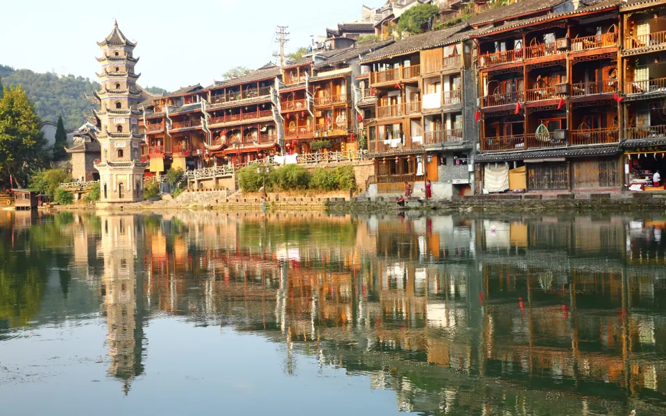 Stilt houses and a pagoda reflected in the Tuojiang at Fenghuang