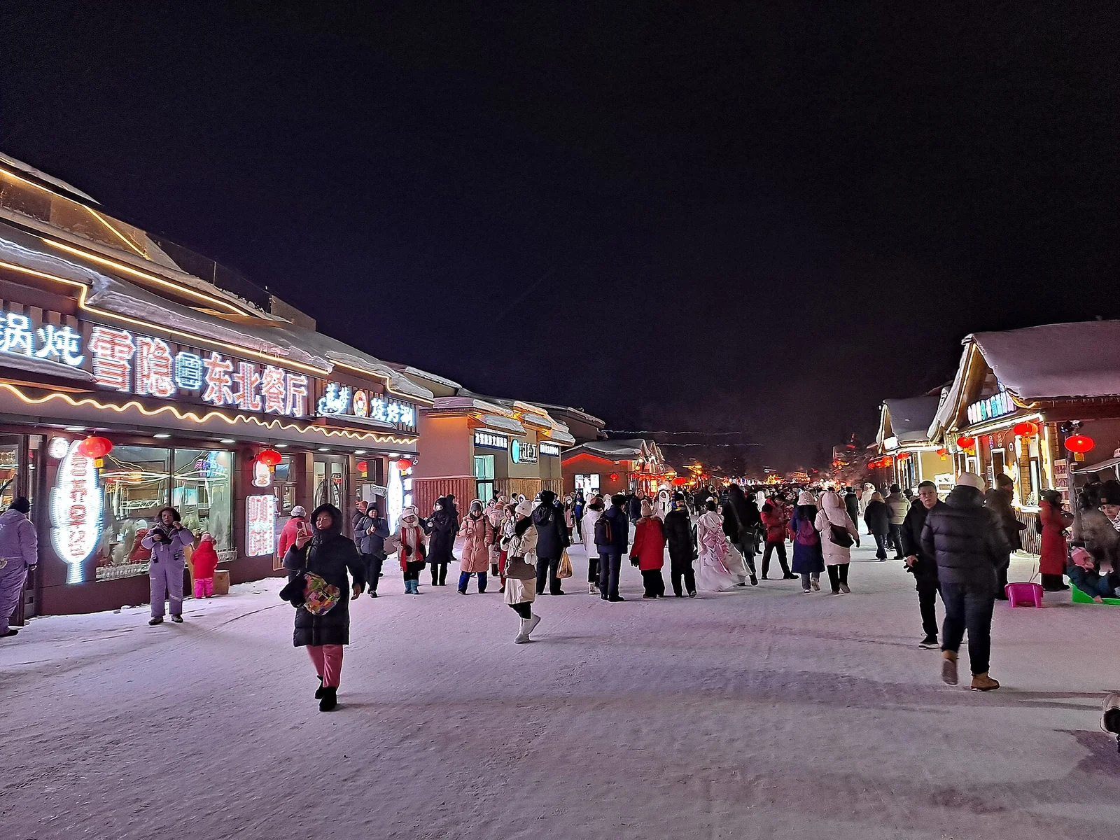 Visitors on a snowy night street in China Snow Town