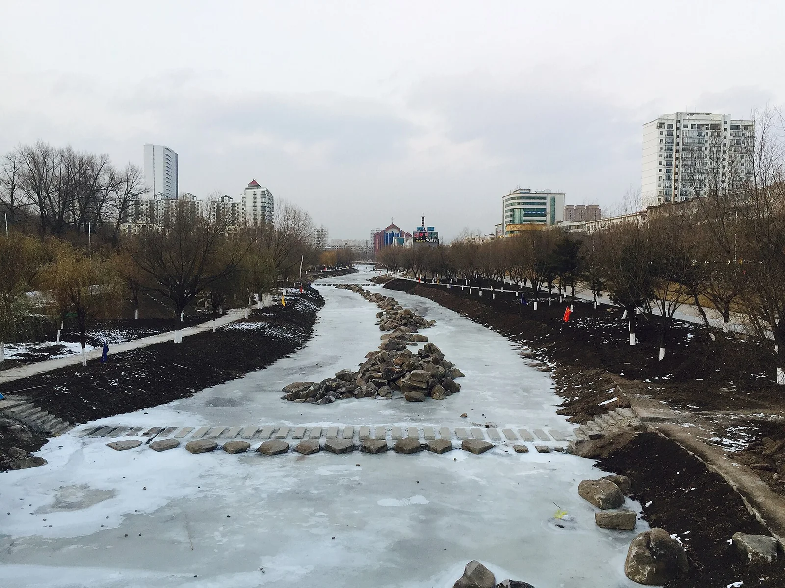 Frozen Yanji River and city buildings in winter
