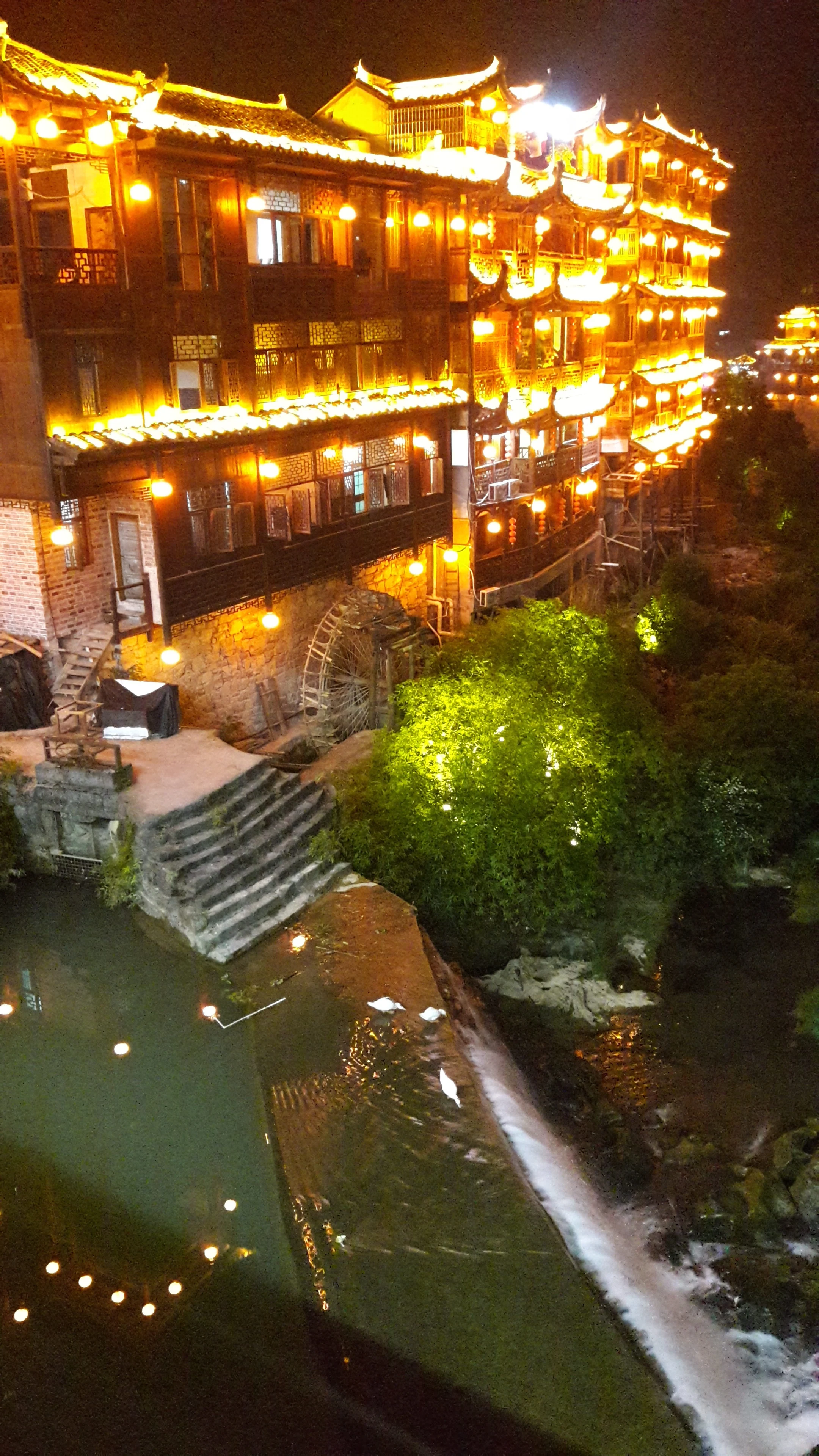 Furong Town waterfall and buildings illuminated at night.
