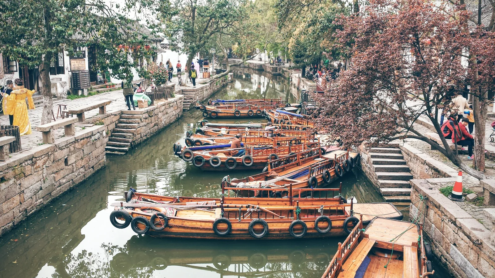 Barcas de madera amarradas a la orilla de piedra de un canal de Tongli