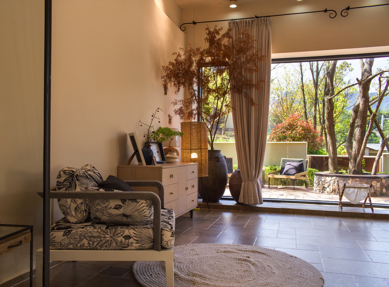 Indoor lounge chair facing a tree-lined outdoor seating area