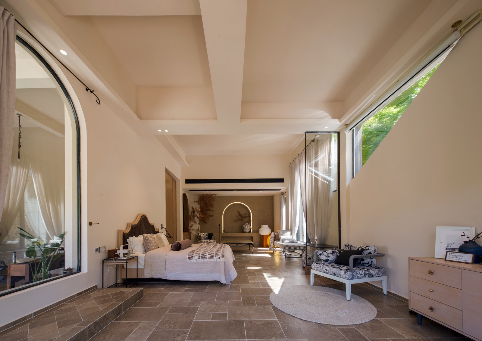 Spacious open-plan guest room with one bed and several lounge chairs